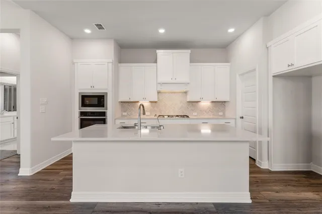 a kitchen with kitchen island sink stove and cabinets
