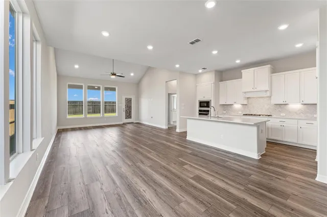 a large kitchen with kitchen island wooden floors white cabinets and stainless steel appliances