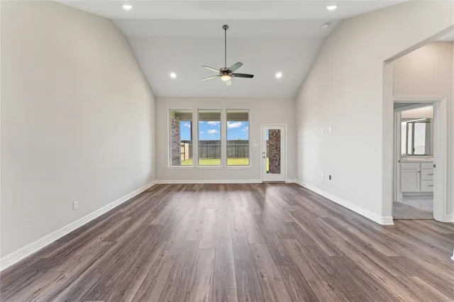 an empty room with wooden floor chandelier and windows