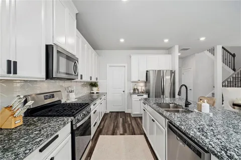 a kitchen with stainless steel appliances granite countertop a sink stove and refrigerator