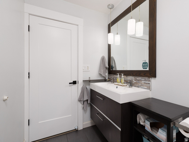 8252 Wood Street Midvale, UT 84047 - Photo 15 of 40 Modern bathroom vanity featuring a rectangular integrated sink, dark wood-finish cabinetry with drawer storage, and a large framed mirror