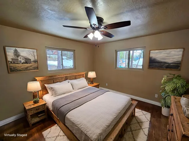 an empty room with wooden floor fan and windows