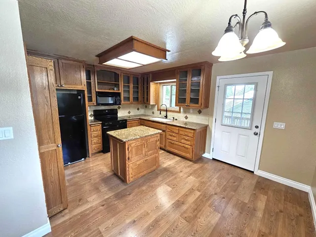 a large kitchen with a refrigerator a stove a sink dishwasher and wooden cabinets