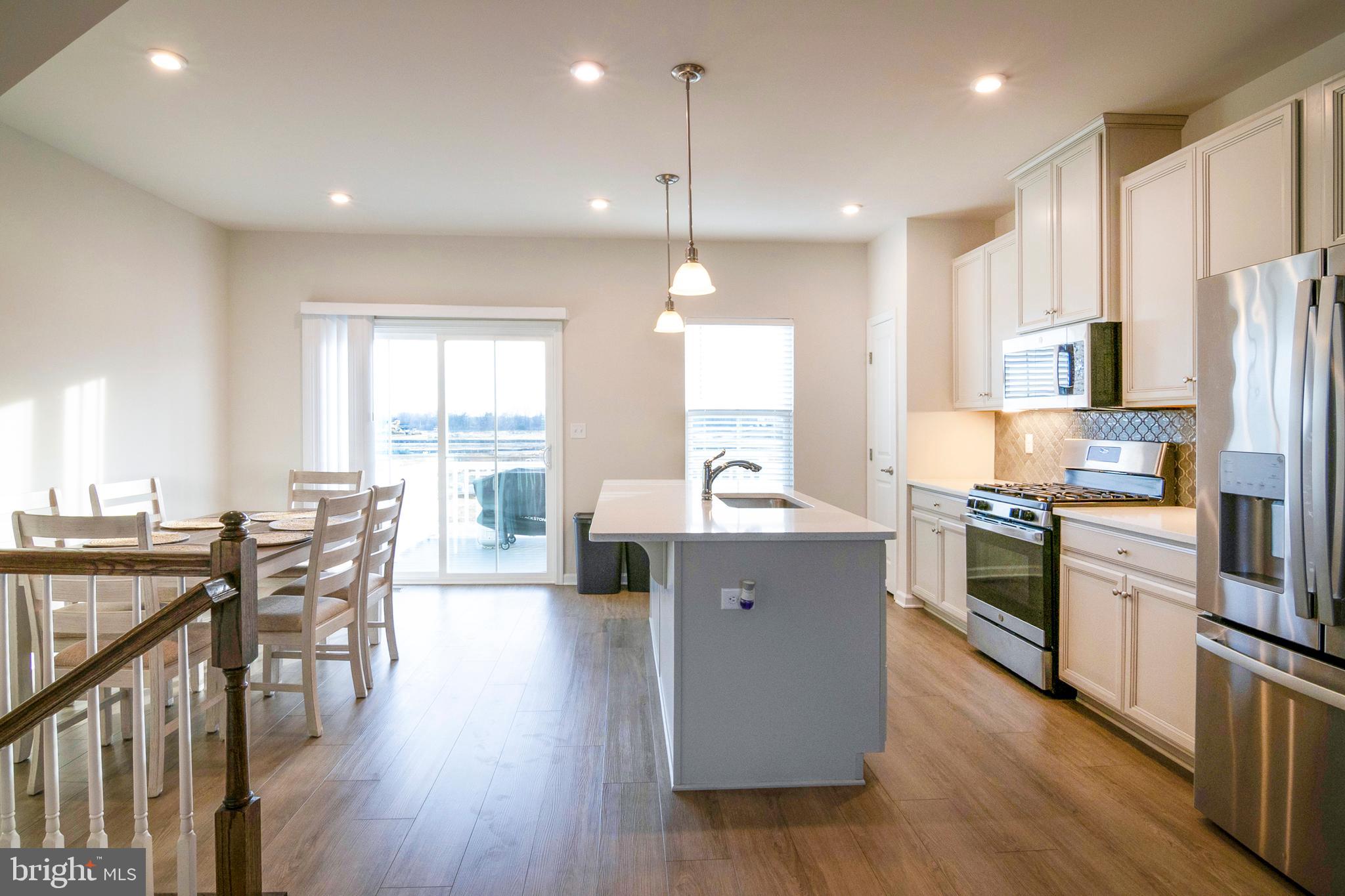 33 Roundstone Run Swedesboro, NJ 08085 - Photo 11 of 43 a kitchen with stainless steel appliances granite countertop a stove top oven a refrigerator a sink a dining table and chairs with wooden floor