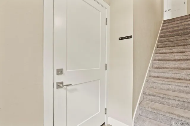 a view of staircase with white walls and white door