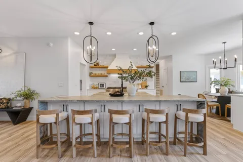 a kitchen with stainless steel appliances kitchen island granite countertop a stove a oven a dining table and chairs with wooden floor