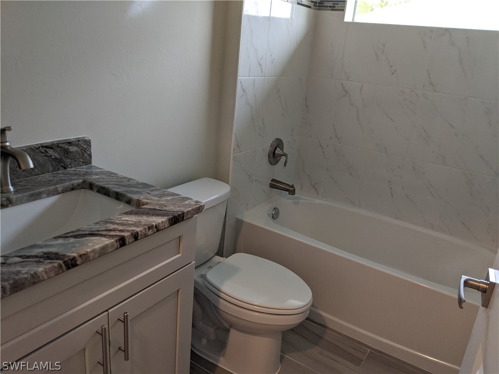 2930 18th Street Southwest Lehigh Acres, FL 33976 - Photo 15 of 20 a bathroom with a granite countertop toilet sink and mirror