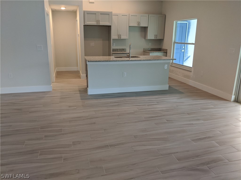 2930 18th Street Southwest Lehigh Acres, FL 33976 - Photo 18 of 20 a view of kitchen and empty room with wooden floor