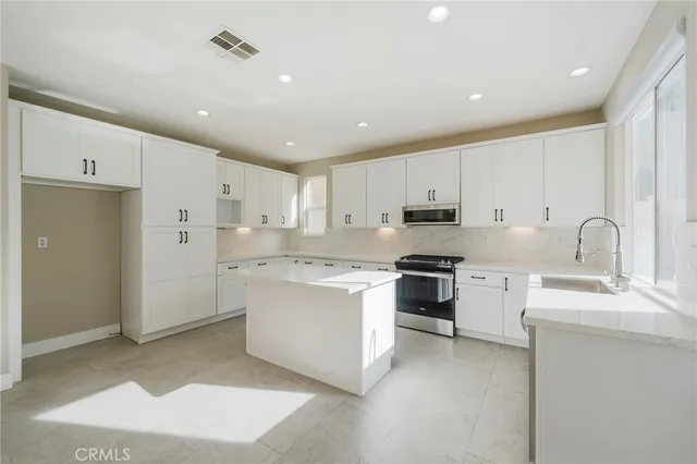 a kitchen with white cabinets and stainless steel appliances