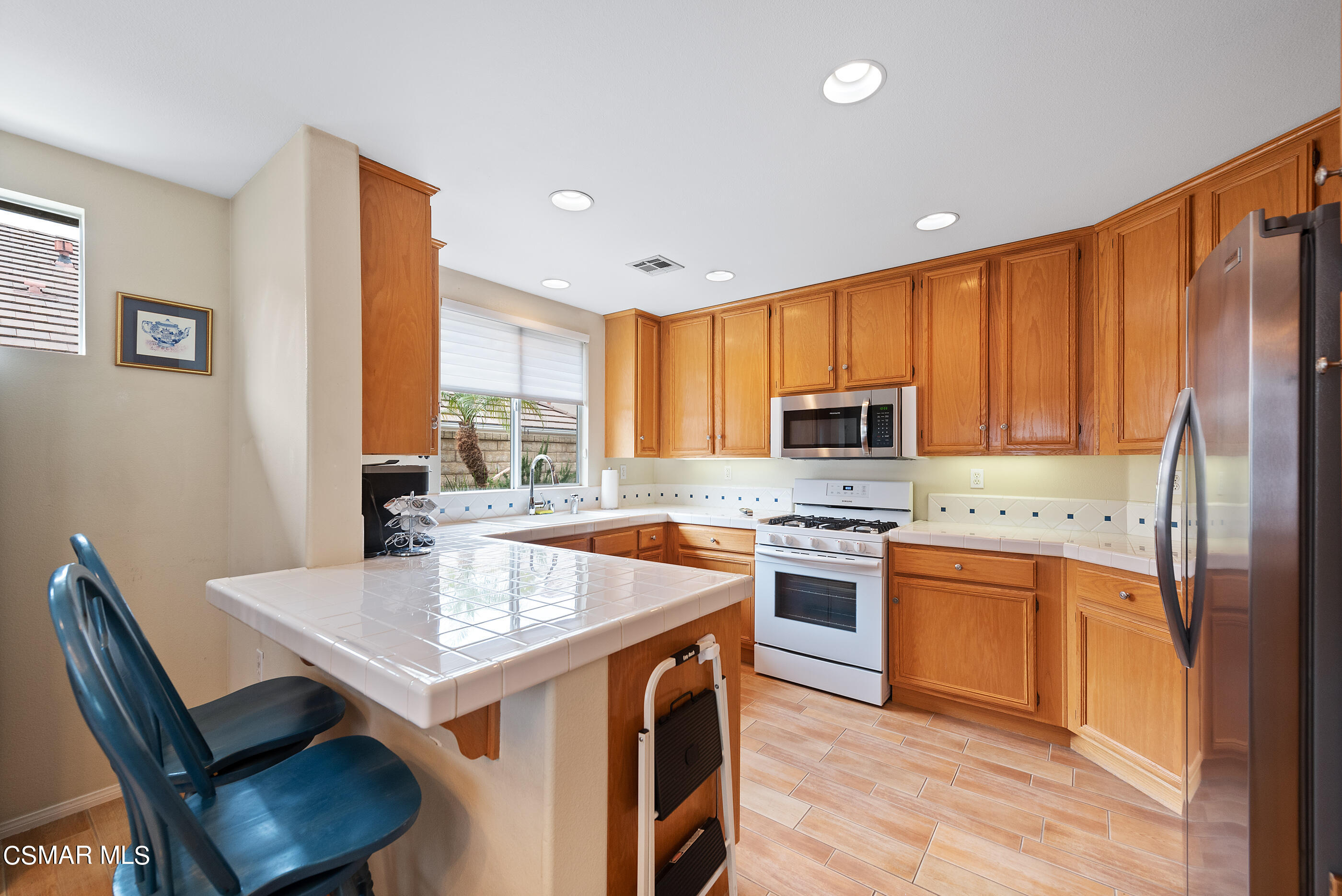 5642 Daisy Street Simi Valley, CA 93063 - Photo 12 of 41 a kitchen with a stove a sink dishwasher a refrigerator with a dining table and chairs
