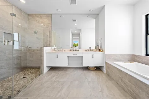 a bathroom with a double vanity sink mirror and bathtub