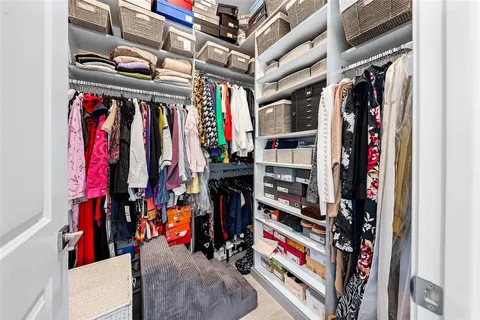 a view of walk in closet with clothes and shoes