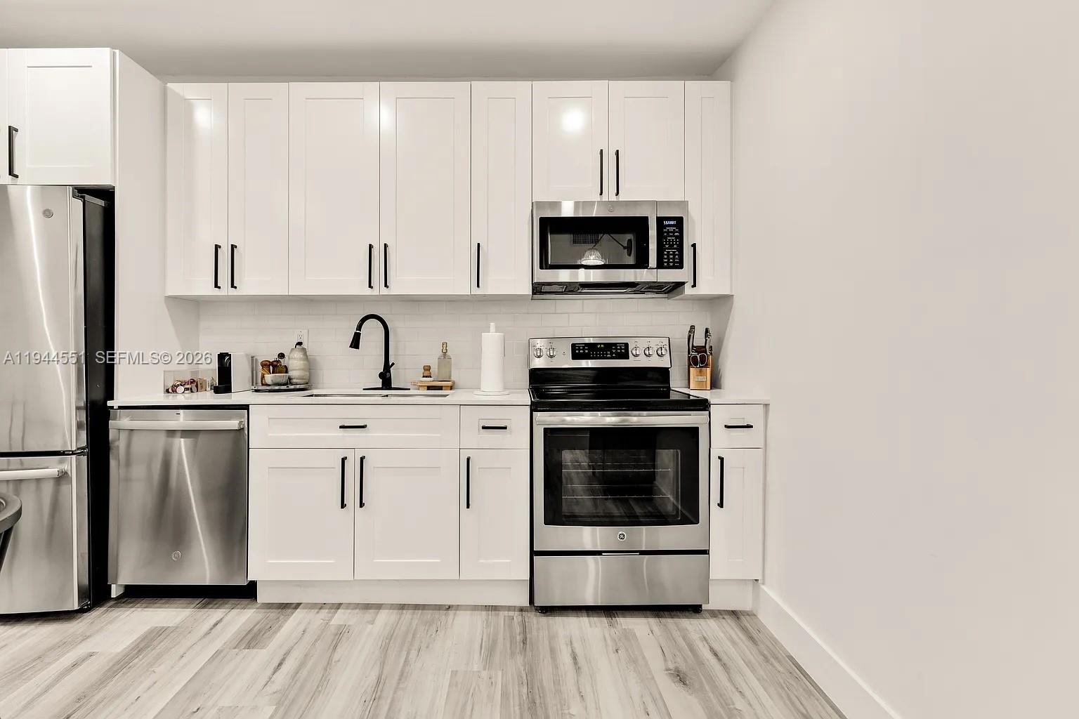 1237 Northwest 33rd Avenue, Unit 1 Miami, FL 33125 - Photo 15 of 22 a kitchen with stainless steel appliances granite countertop a stove a microwave and a refrigerator