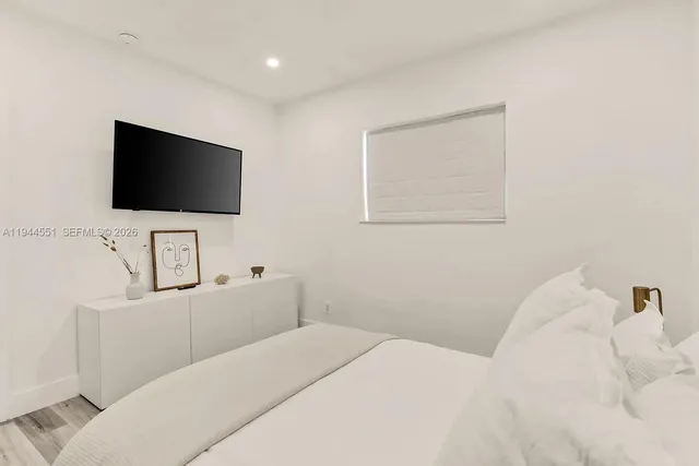 a bedroom with a bed a flat screen tv and a window