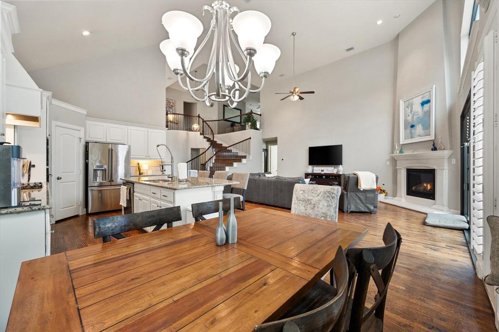 6713 Matador Ranch Road North Richland Hills, TX 76182 - Photo 11 of 39 Dining area with a ceiling fan, a chandelier, dark wood-style floors, a glass covered fireplace, and vaulted ceiling