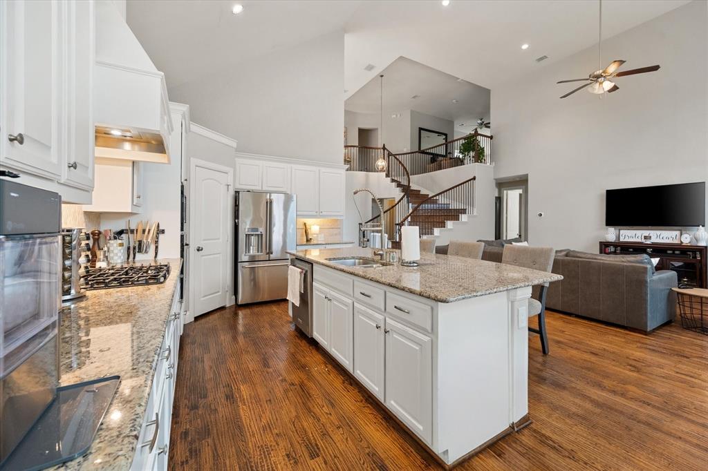 6713 Matador Ranch Road North Richland Hills, TX 76182 - Photo 39 of 39 Kitchen with white cabinetry, open floor plan, light stone countertops, a kitchen bar, and lofted ceiling