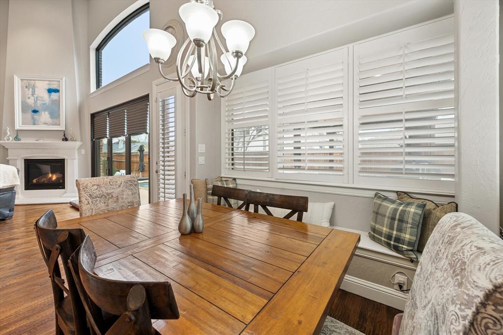 6713 Matador Ranch Road North Richland Hills, TX 76182 - Photo 13 of 39 Dining space featuring a chandelier, a glass covered fireplace, wood finished floors, and a high ceiling