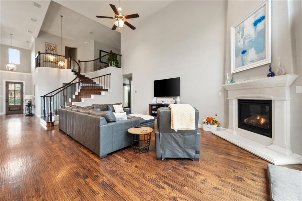 6713 Matador Ranch Road North Richland Hills, TX 76182 - Photo 14 of 39 Living area featuring a ceiling fan, a high ceiling, dark wood finished floors, and a glass covered fireplace