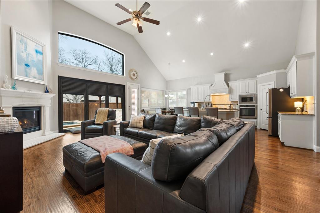 6713 Matador Ranch Road North Richland Hills, TX 76182 - Photo 16 of 39 Living area featuring ceiling fan, a glass covered fireplace, lofted ceiling, recessed lighting, and dark wood-type flooring