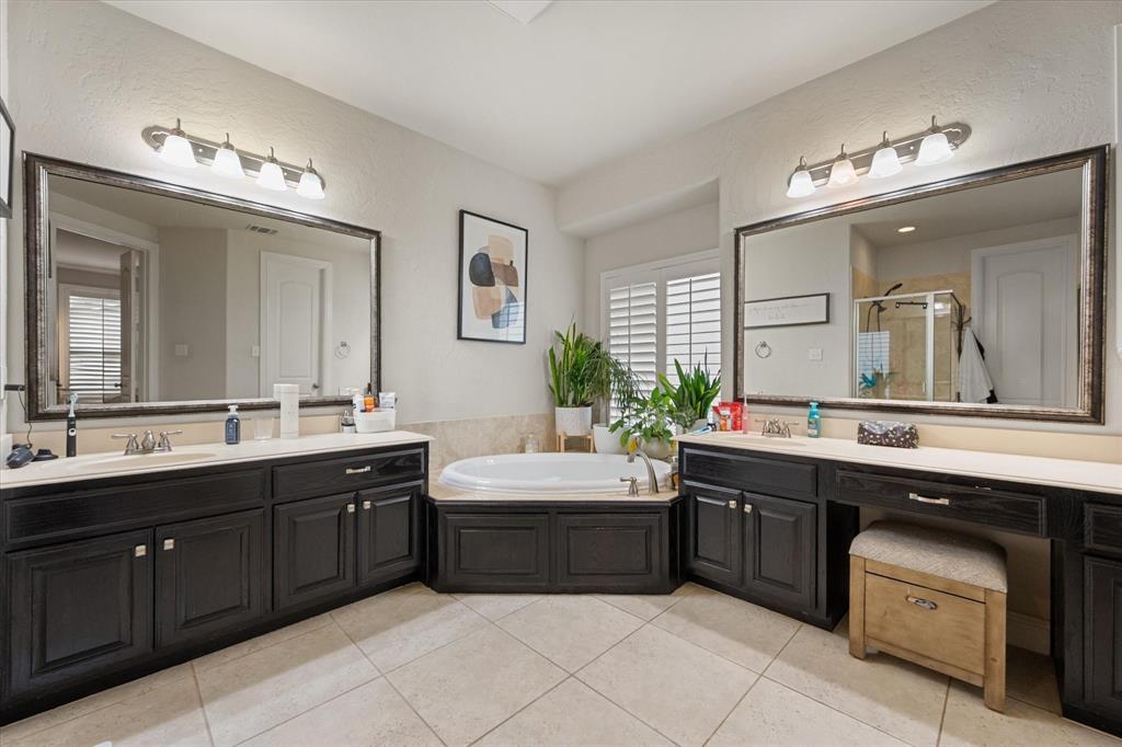 6713 Matador Ranch Road North Richland Hills, TX 76182 - Photo 20 of 39 Full bathroom featuring two vanities, a bath, a stall shower, light tile patterned floors, and a textured wall
