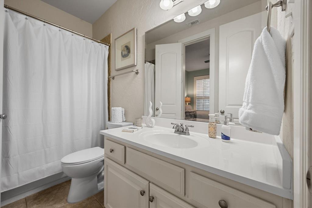 6713 Matador Ranch Road North Richland Hills, TX 76182 - Photo 30 of 39 Bathroom with vanity, curtained shower, dark tile patterned floors, and a textured wall