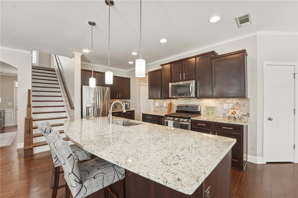 3330 Camelot Way Cumming, GA 30040 - Photo 12 of 47 a kitchen with stainless steel appliances granite countertop a table chairs and a refrigerator
