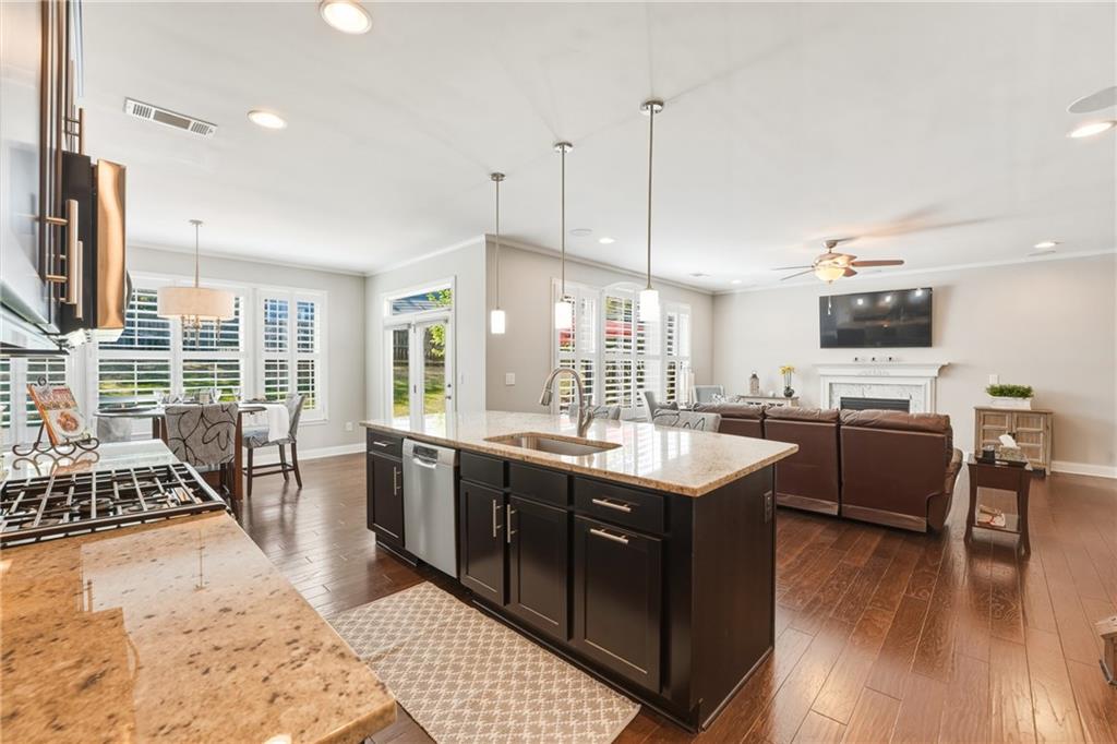 3330 Camelot Way Cumming, GA 30040 - Photo 13 of 47 a open kitchen with stainless steel appliances granite countertop a stove top oven a sink dishwasher a dining table and chairs with wooden floor