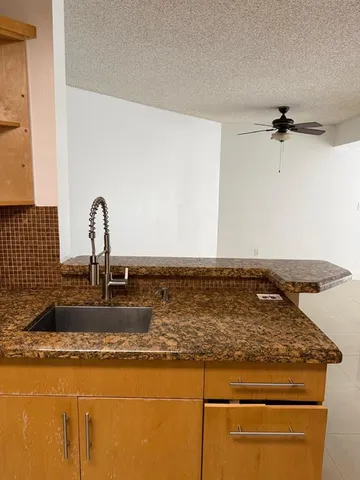 a kitchen with kitchen island granite countertop a refrigerator stove and sink