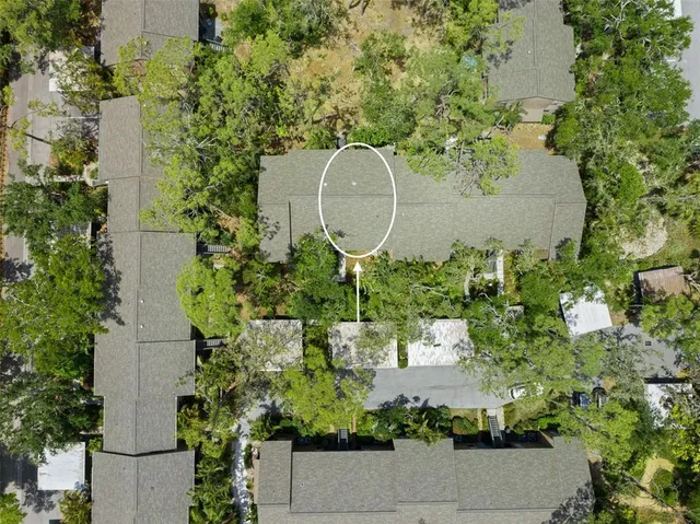 an aerial view of a house with a yard and trees all around