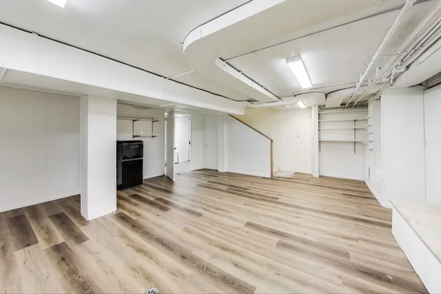 a view of empty room with wooden floor and kitchen view