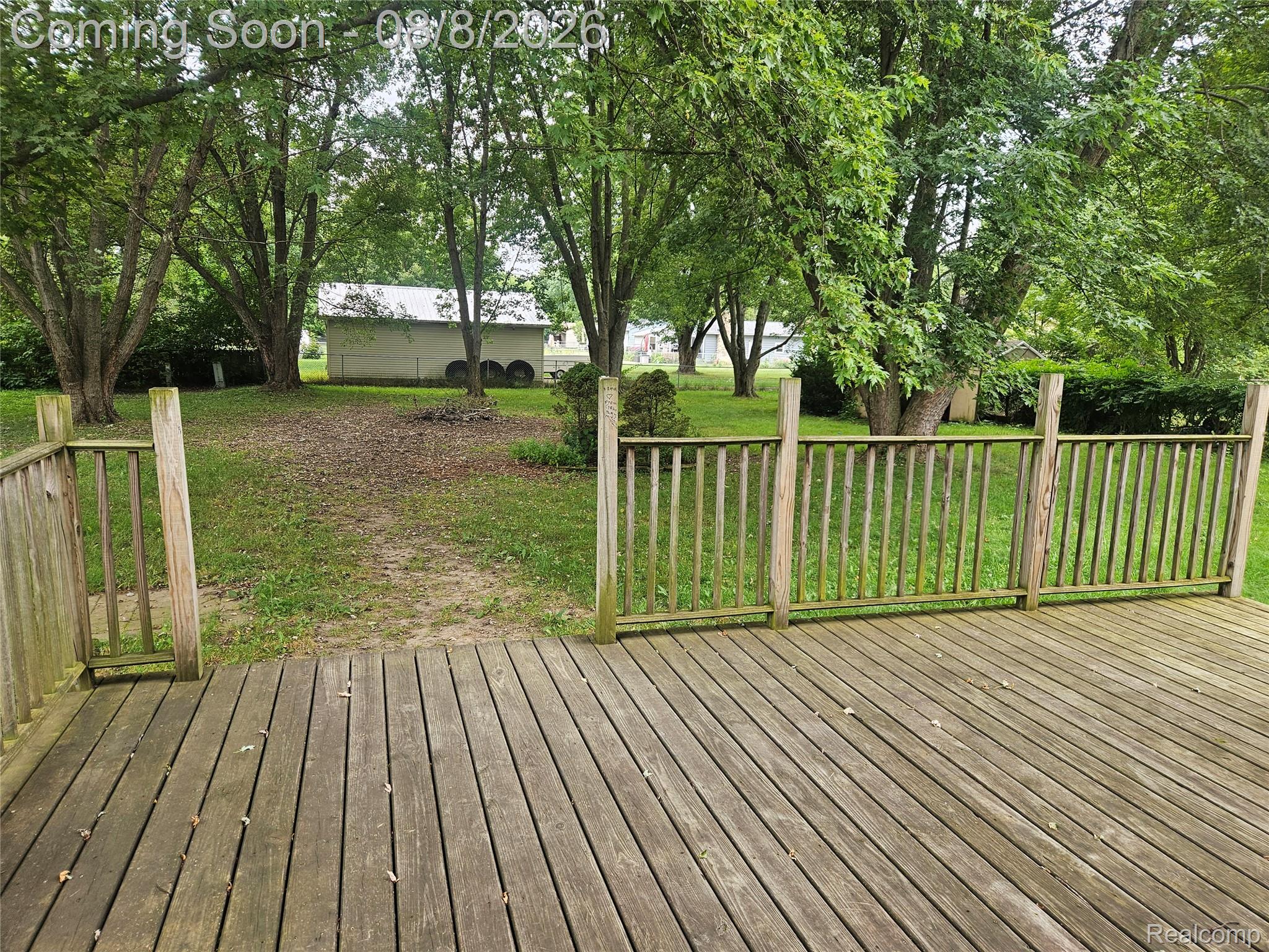 4507 West Wilson Road Clio, MI 48420 - Photo 14 of 14 Exterior wood deck with a slatted railing overlooking a grassy yard with mature trees