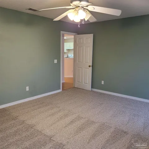 an empty room with a chandelier fan and wooden floor