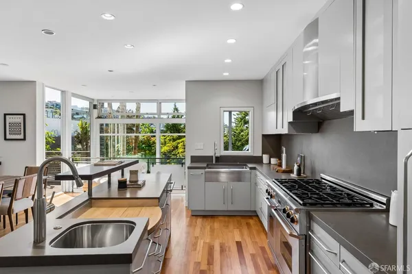 a kitchen that has a sink a stove and a wooden floors with cabinets