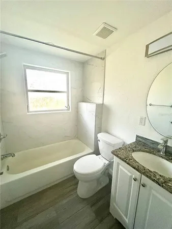 a bathroom with a granite countertop toilet a sink and a bathtub