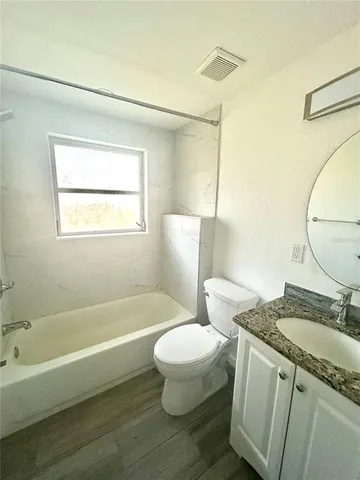 a bathroom with a granite countertop toilet a sink and a bathtub
