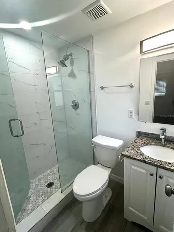 a bathroom with a granite countertop sink a toilet and shower