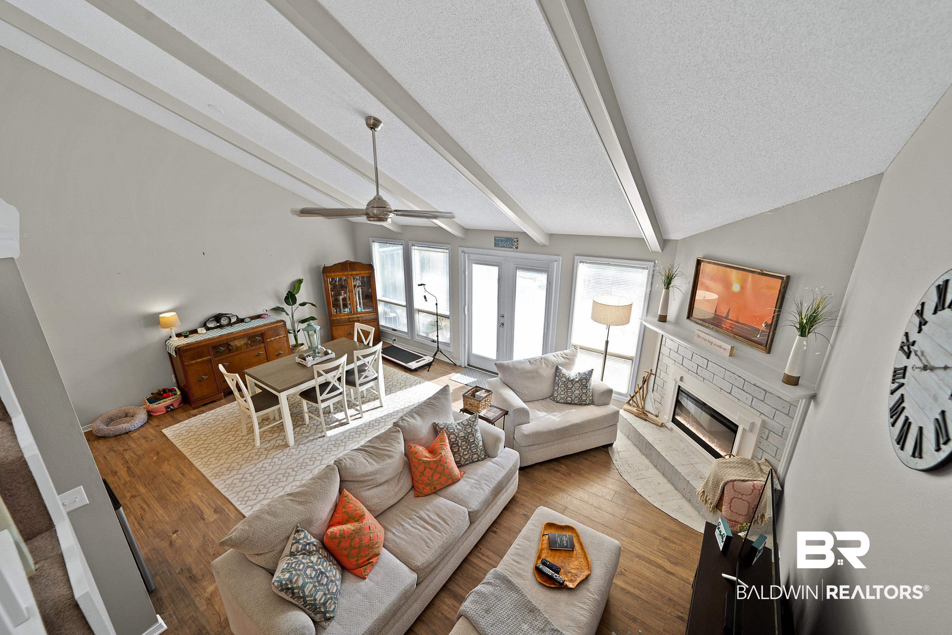 1701 Regency Road, Unit 106 Gulf Shores, AL 36542 - Photo 9 of 42 Living room with a brick fireplace, wood finished floors, a ceiling fan, a textured ceiling, and french doors