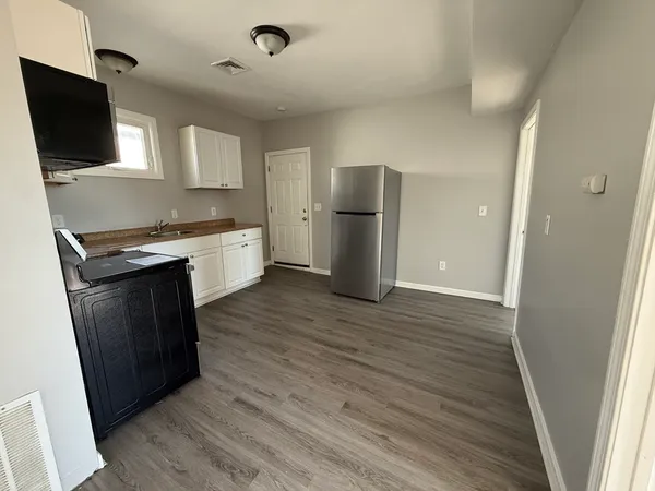 a kitchen with a refrigerator a sink and wooden floor