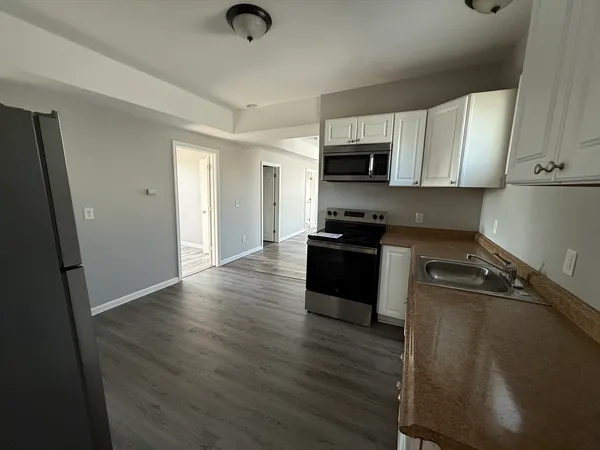 a kitchen with stainless steel appliances granite countertop a refrigerator a stove top oven a sink and dishwasher with wooden floor