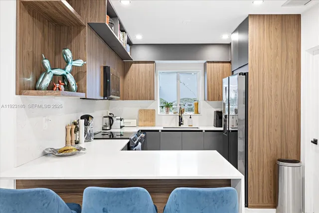 a kitchen with stainless steel appliances granite countertop a refrigerator a sink dishwasher a stove and a dining table with wooden floor