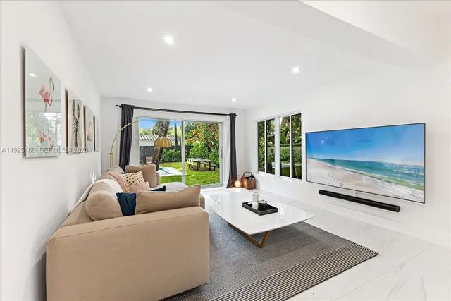 a living room with furniture floor to ceiling window and a flat screen tv