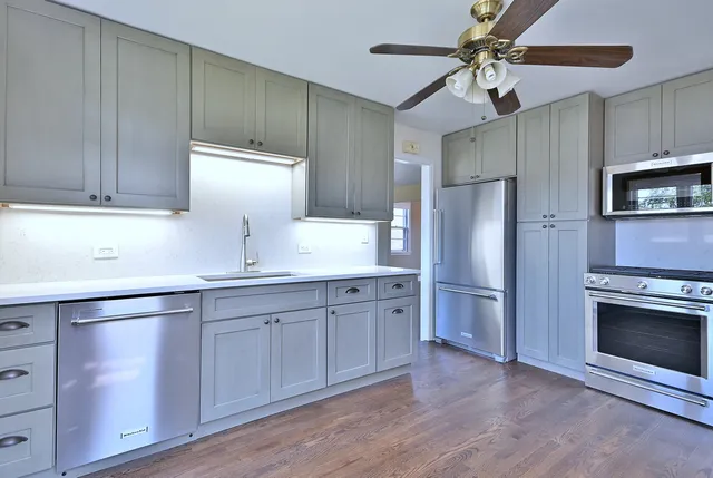 a kitchen with stainless steel appliances a refrigerator a sink and white cabinets