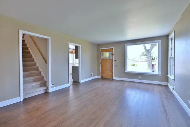an empty room with wooden floor cabinet and windows