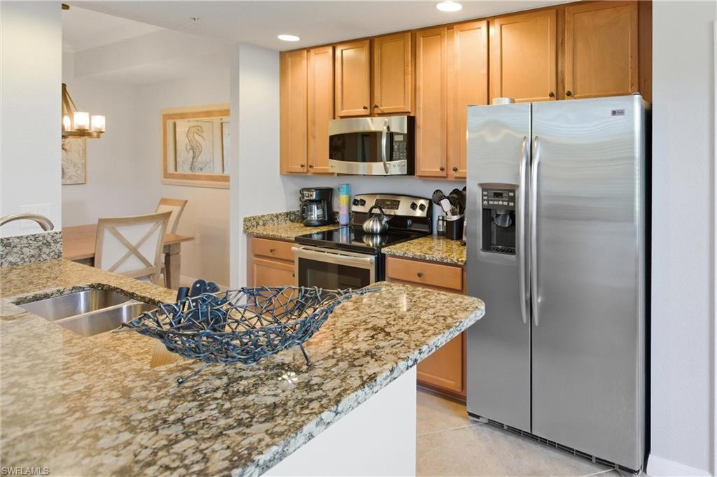 9844 Venezia Circle, Unit 714 Naples, FL 34113 - Photo 16 of 50 a kitchen with stainless steel appliances granite countertop a refrigerator and a stove top oven