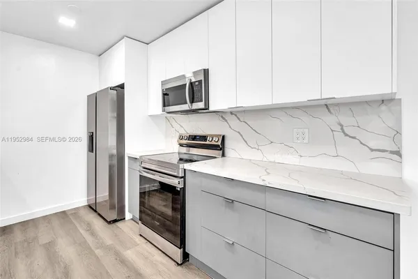 a kitchen with stainless steel appliances granite countertop white cabinets and a stove