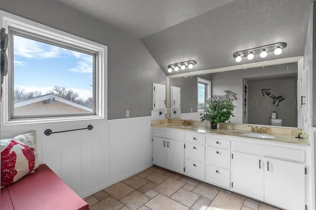 a bathroom with a granite countertop tub a double vanity sink a window and a mirror