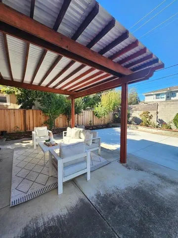 a view of patio with a table and chairs under an umbrella with a small yard