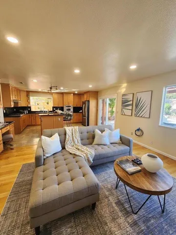 a living room with furniture kitchen view and a wooden floor