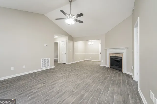 an empty room with wooden floor fireplace and windows