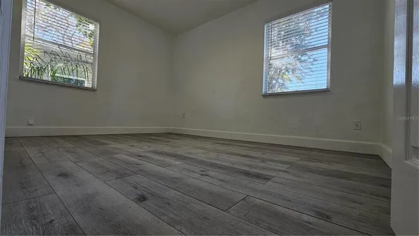 an empty room with wooden floor and windows